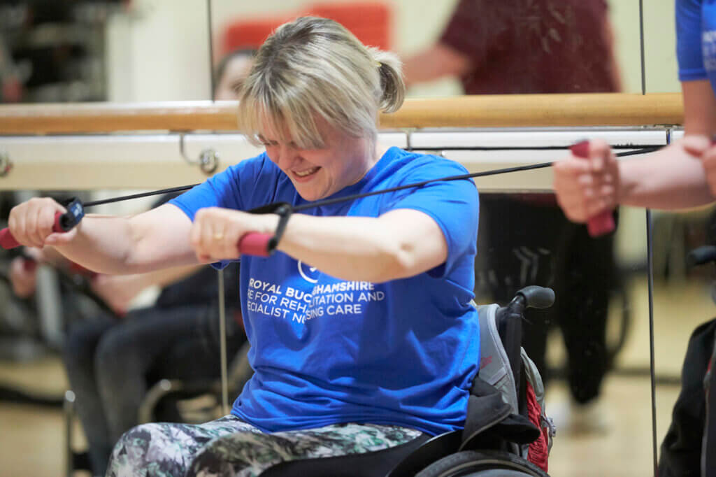 Female wheelchair user stretching with resistance bands in gym