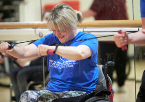 Female wheelchair user stretching with resistance bands in gym