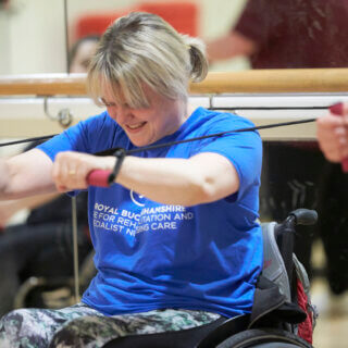 Female wheelchair user stretching with resistance bands in gym