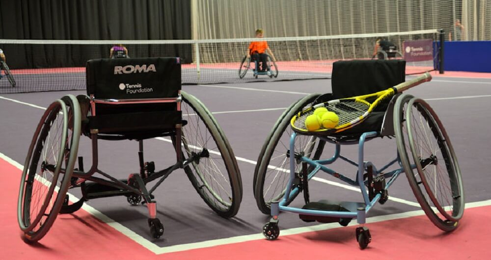 two tennis sports wheelchairs with a tennis racket and tennis balls