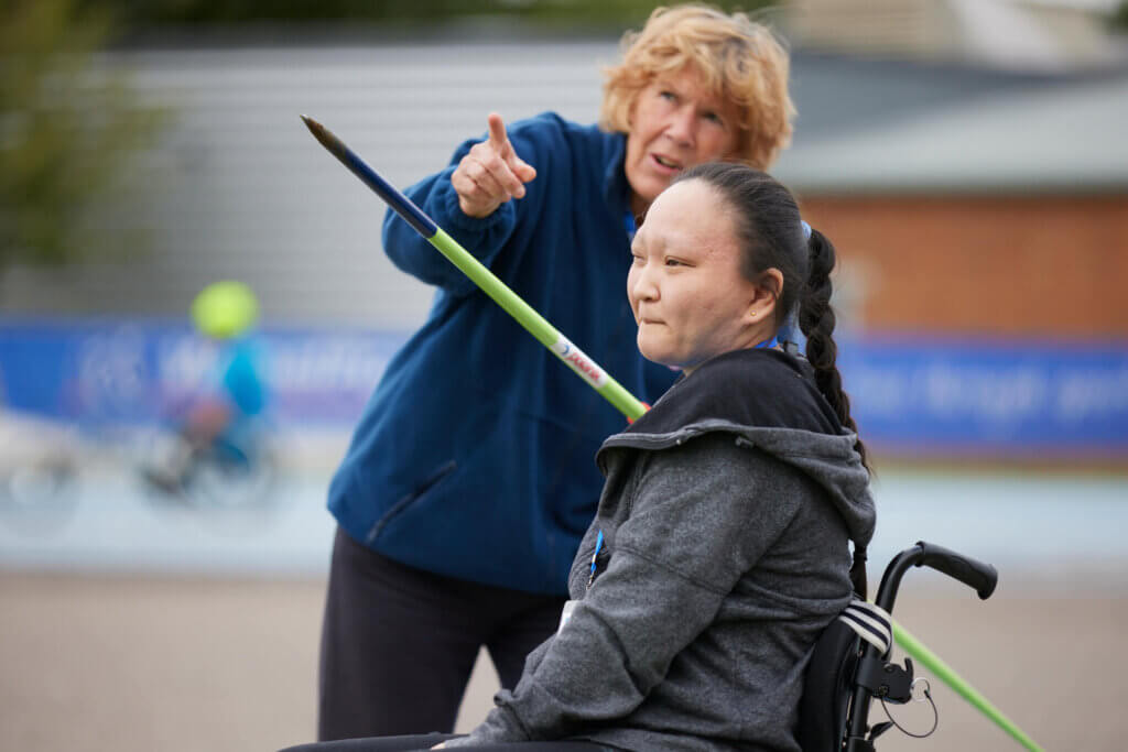 Volunteer talking to a seated javelin athlete