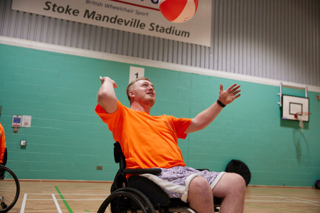 Recently paralysed male trying volleyball at the 2023 Inter Spinal Unit Games