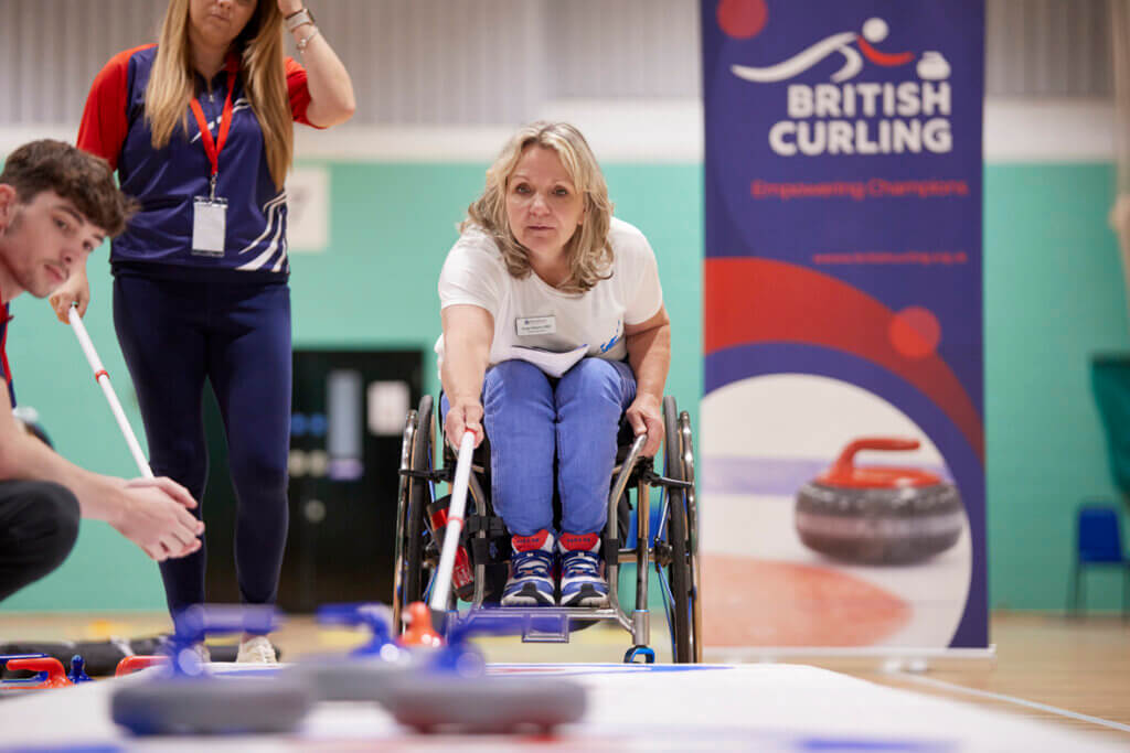 Angie Malone MBE demonstrating wheelchair curling at Stoke Mandeville Stadium