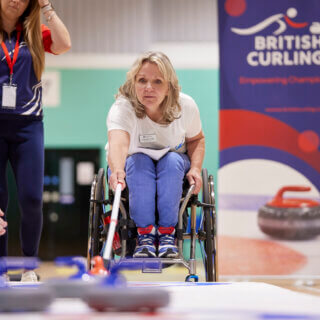 Angie Malone MBE demonstrating wheelchair curling at Stoke Mandeville Stadium